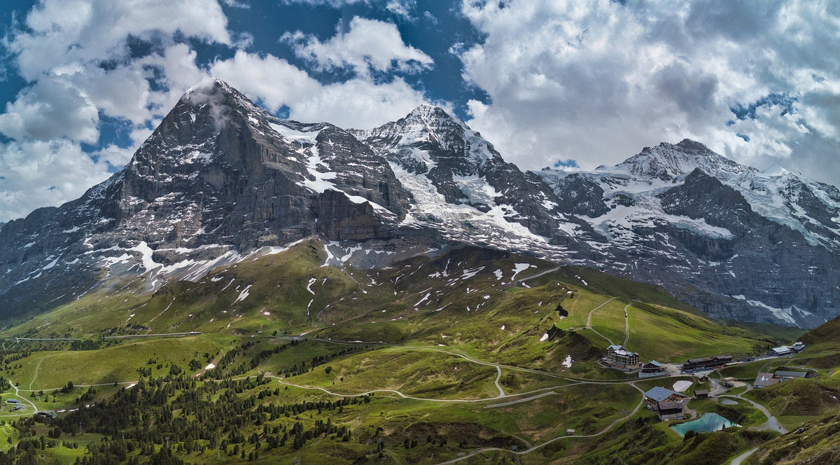 Eiger, Mönch och Jungfrau sedda från Kleine Scheidegg en sommardag, med gröna betesmarker nedanför bergväggen