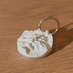 Kebnekaise nyckelring i rostfritt stål med 3D-topografi av toppkammen, på ett ekbord - 3D-rendering av den riktiga modellen